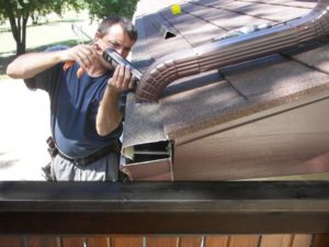 Roof gutter installation by worker with equipments