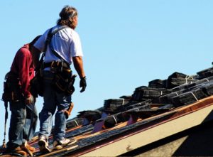 Workers measure the defective roof for replacement.